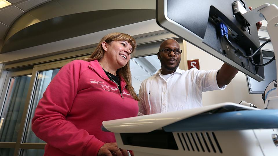 Student and instructor looking at a computer screen in a medical room