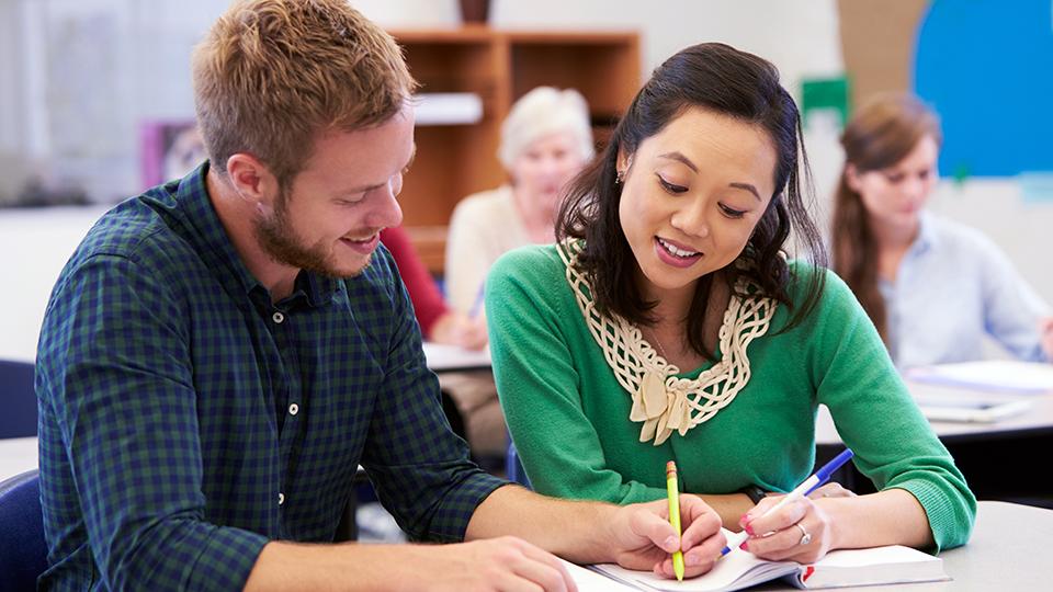 Two students examine a paper together.