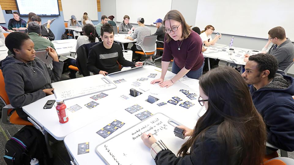  A teacher helps a group of students understand a chemistry assignment.