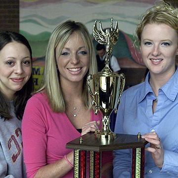 Three female students pose with a trophy.