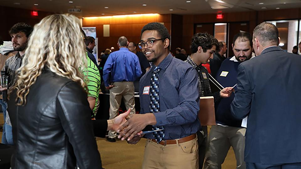 Student shaking hands with a business recruiter at a career fair