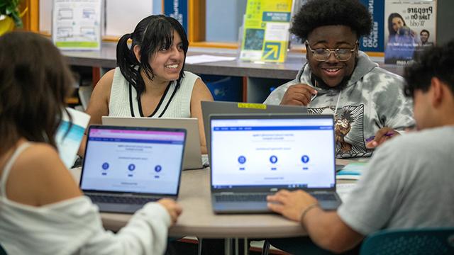 Students seated at a round table using laptops