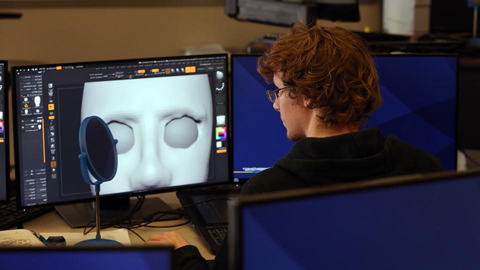 Student working in the animation lab showing his art on a computer monitor