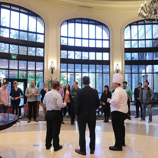 Students exploring large hotel lobby while listening to a chef speaking