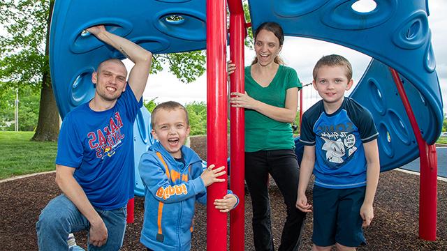 Tyler Pennington under a brightly colored tent with his wife and two young sons