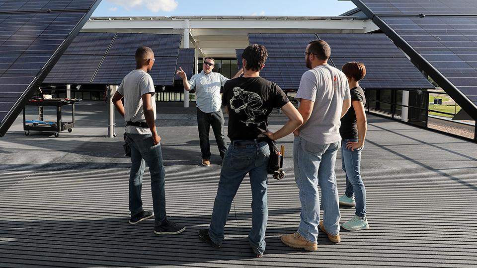 Students listening to a lecture among the solar panels outside the CTEC building.